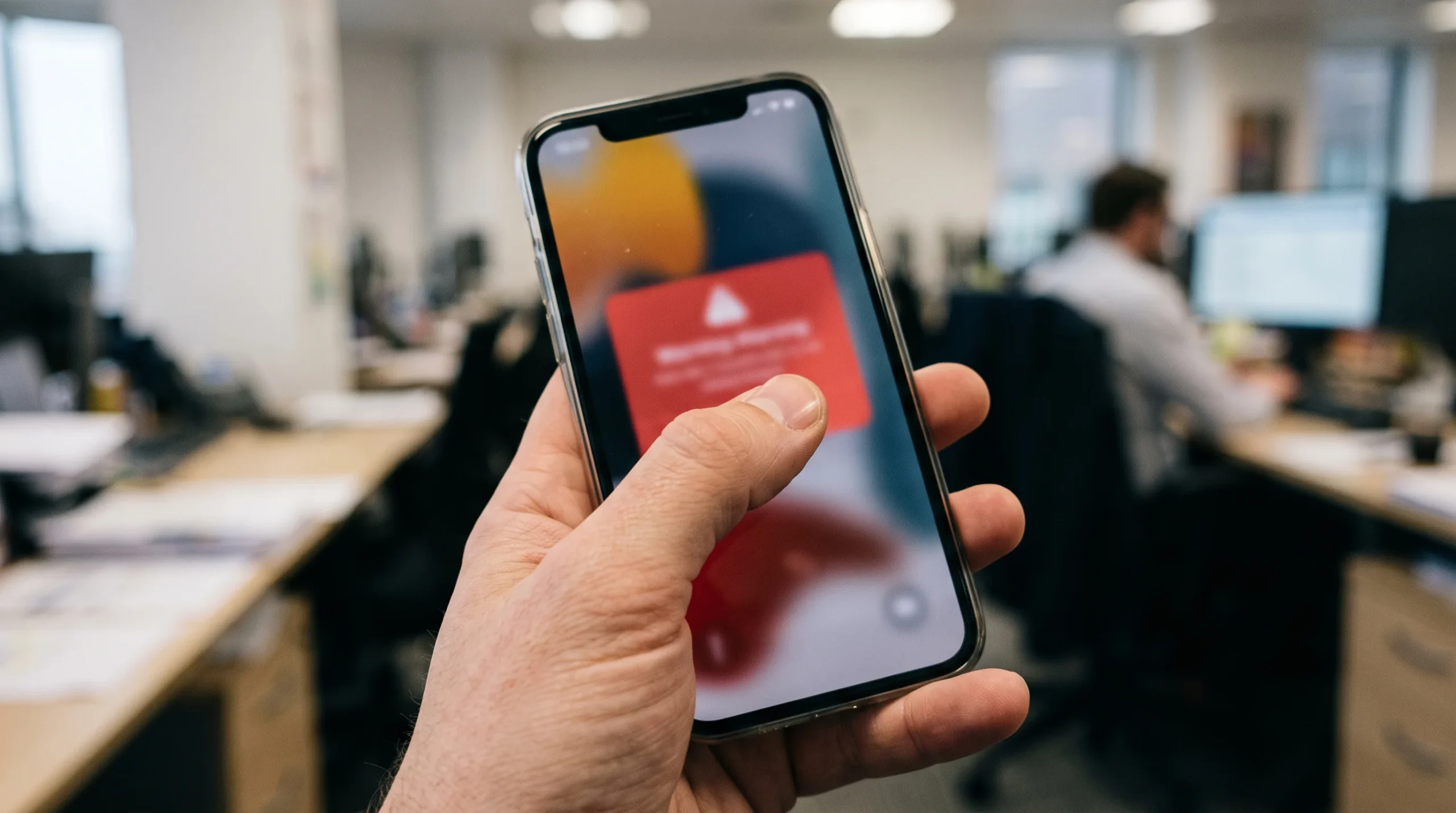 Hand covering a phone screen showing a warning pop-up about a suspicious offer