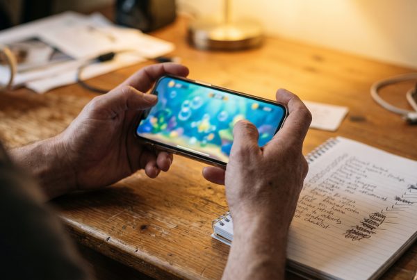 Person checking a fish table casino site on a smartphone with a checklist notebook nearby (includes the focus keyphrase)